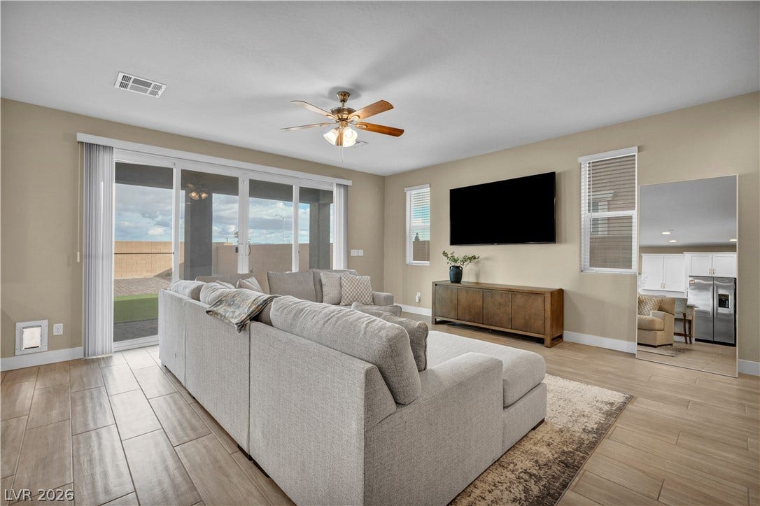 7128 Port Stephens Street, North Las Vegas, NV 89084 Sliding glass doors open to the outdoors in a spacious living area with wood-look flooring.