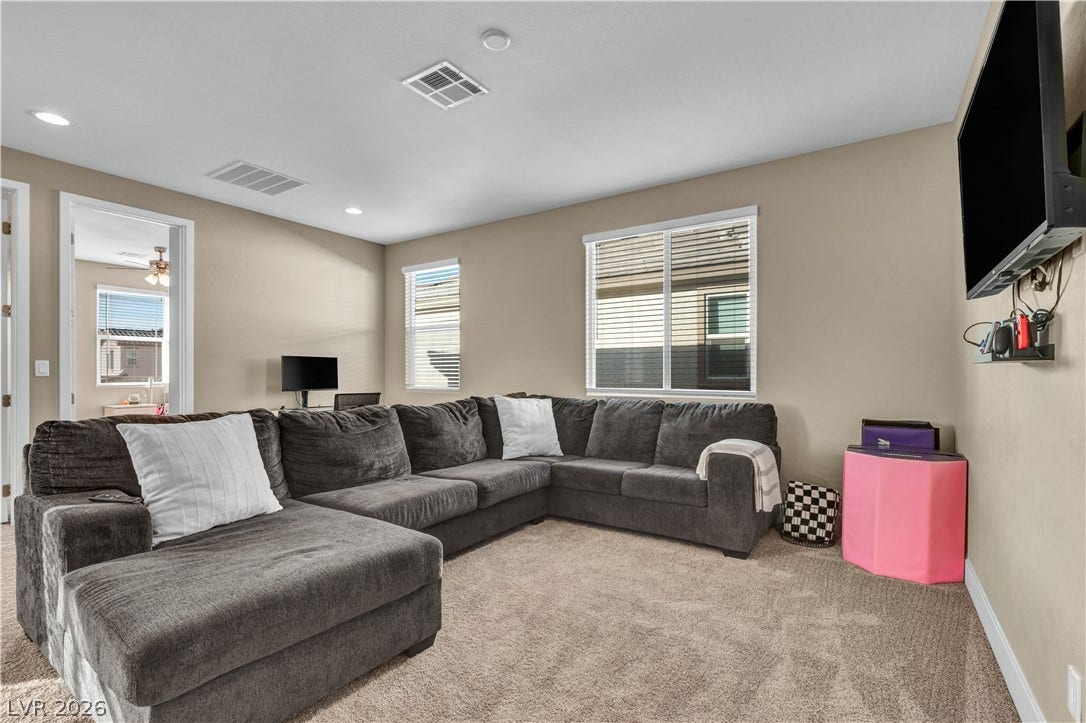 7128 Port Stephens Street, North Las Vegas, NV 89084 Natural light streams through multiple windows onto the comfortable carpeted living space.