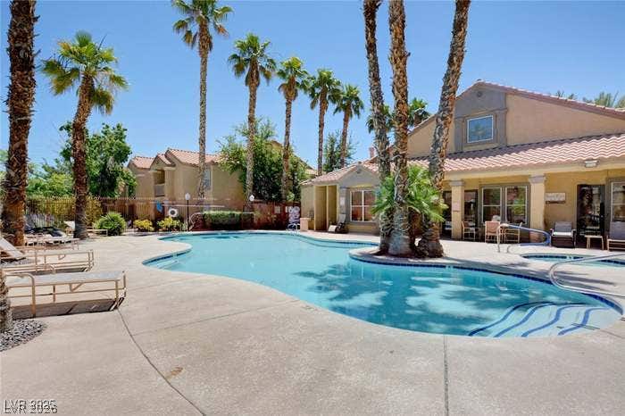 2300 E Silverado Ranch Boulevard, #1077, Las Vegas, NV 89183 Palm trees surround a curved pool alongside the tiled-roof clubhouse patio.