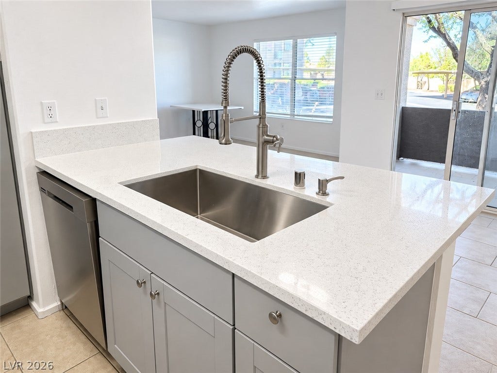 2300 E Silverado Ranch Boulevard, #1077, Las Vegas, NV 89183 An open kitchen island features quartz countertops and a modern undermount stainless steel sink.