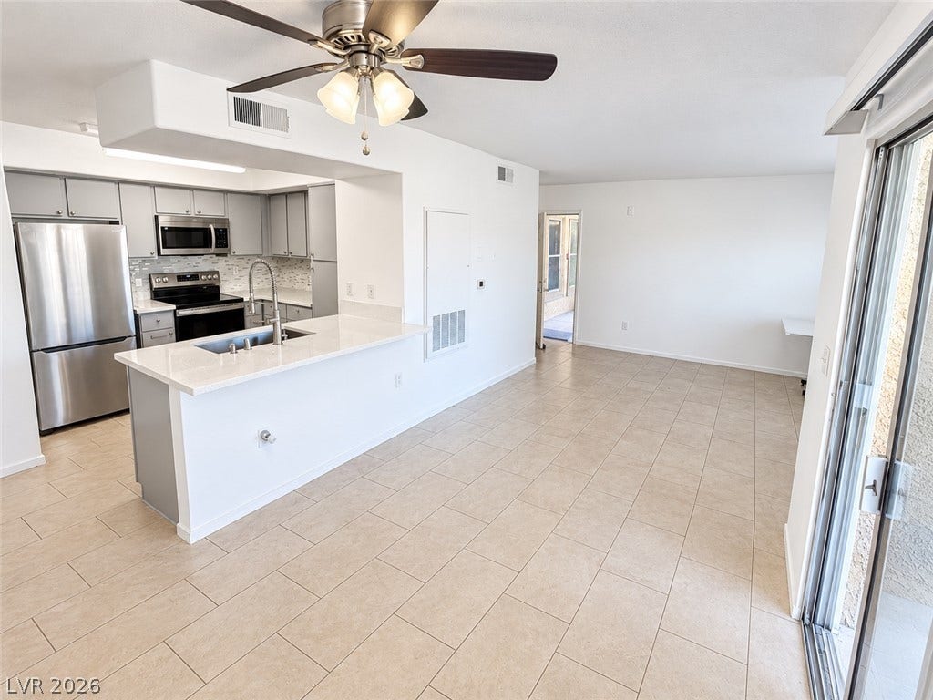 2300 E Silverado Ranch Boulevard, #1077, Las Vegas, NV 89183 Tile flooring spans from the open living area into the updated kitchen with sliding door access.