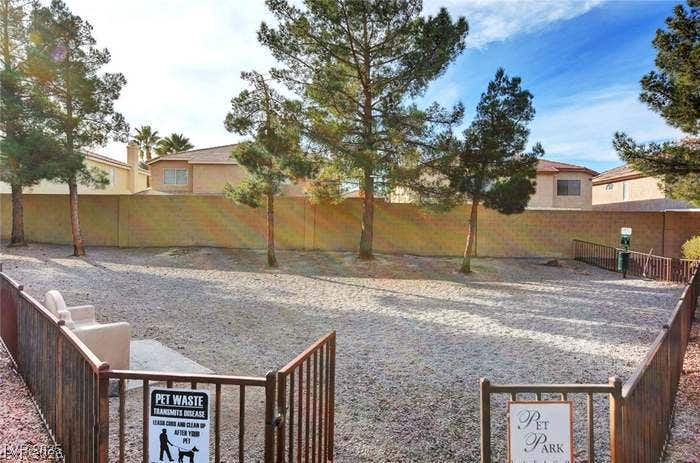 2300 E Silverado Ranch Boulevard, #1077, Las Vegas, NV 89183 Mature trees shade a spacious and fully enclosed community dog park under bright blue skies.