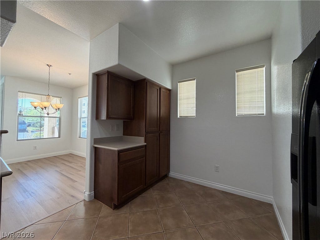 8777 W Maule Avenue, #1158, Las Vegas, NV 89148 Tiled flooring and wood cabinetry define this versatile kitchen space opening to a dining area.