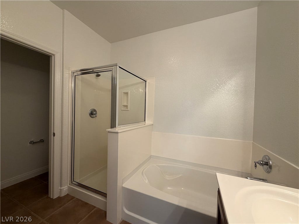 8777 W Maule Avenue, #1158, Las Vegas, NV 89148 A glass-enclosed shower stands adjacent to a built-in soaking tub in this functional bathroom.