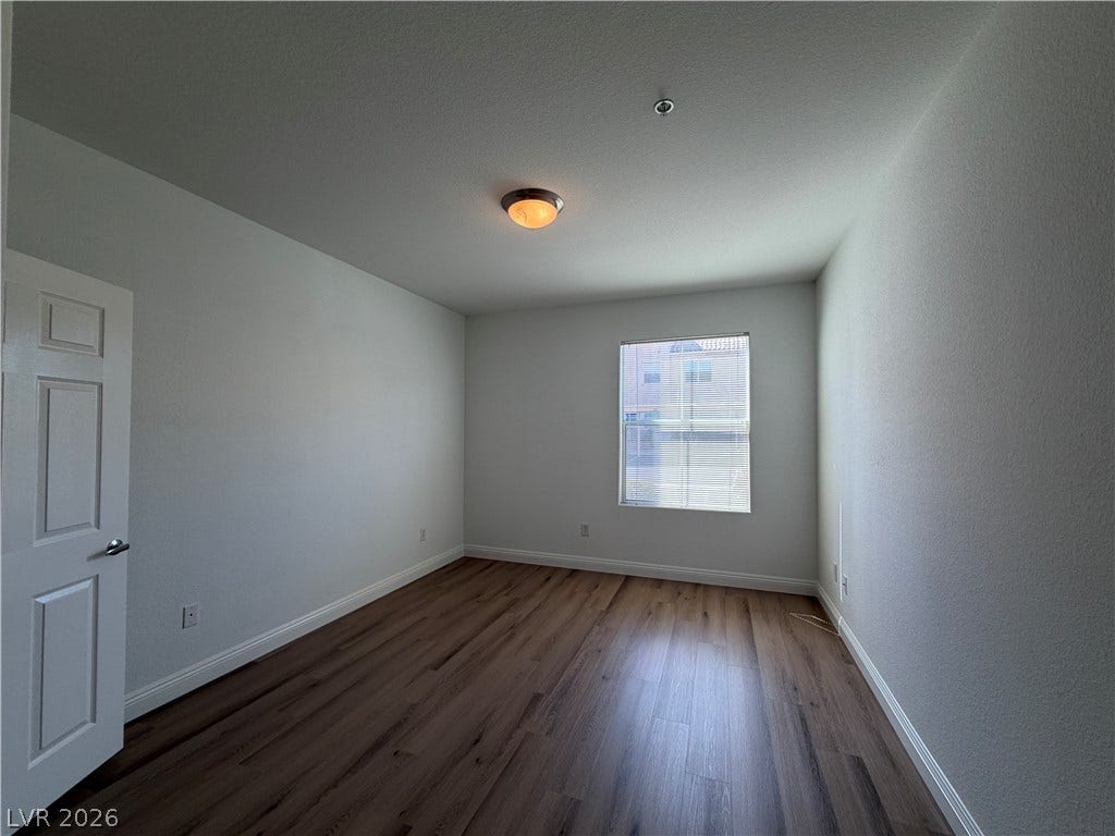 8777 W Maule Avenue, #1158, Las Vegas, NV 89148 Rich wood-inspired flooring and crisp baseboards frame a quiet, light-filled bedroom space.