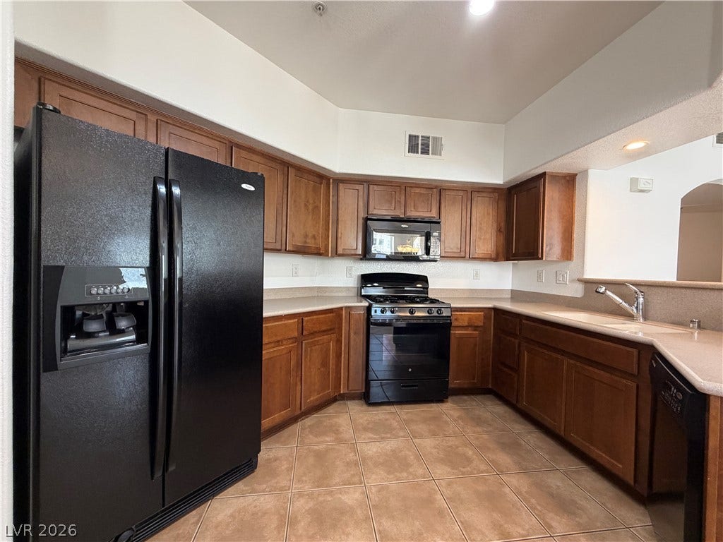 8777 W Maule Avenue, #1158, Las Vegas, NV 89148 Rich wood cabinetry and classic tile flooring define this functional u-shaped kitchen space.