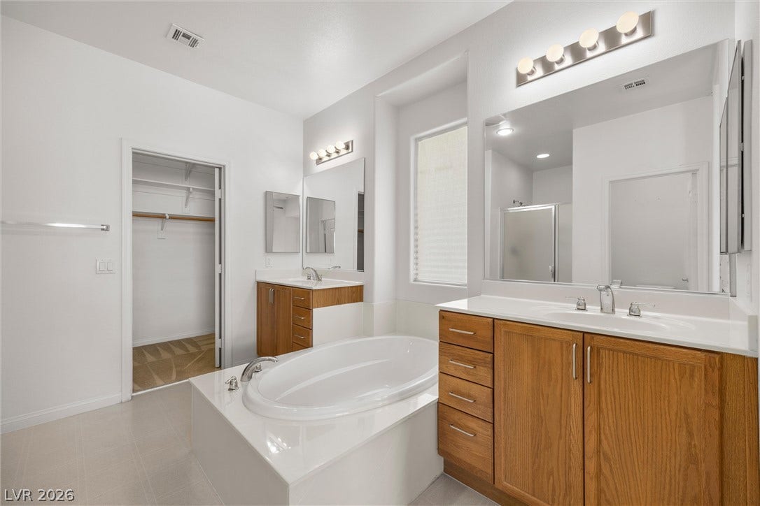 5824 Pleasant Palms Street, North Las Vegas, NV 89081 Double vanities flank a central soaking tub under high ceilings in this bathroom.