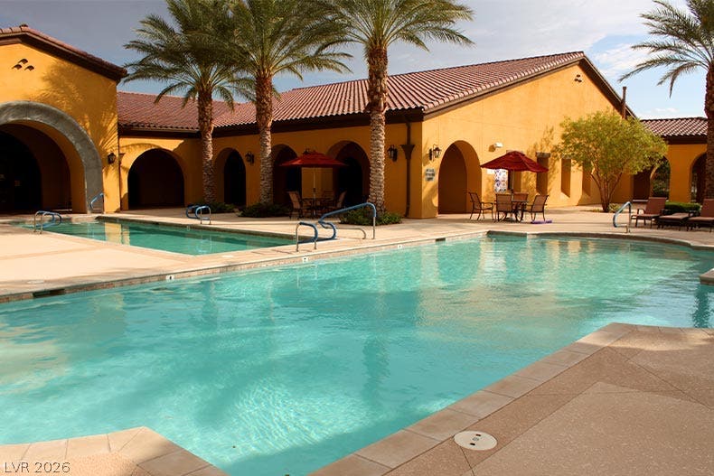5824 Pleasant Palms Street, North Las Vegas, NV 89081 Palm trees frame a sparkling community pool lined with Mediterranean-style architecture and tile roofing.