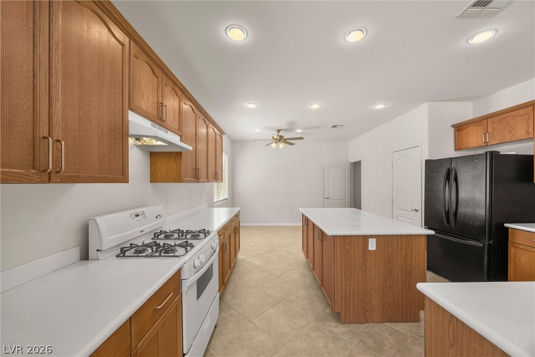 5824 Pleasant Palms Street, North Las Vegas, NV 89081 Warm wood cabinetry and a central island ground this open kitchen with tiled flooring.