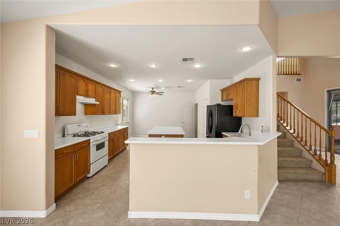 5824 Pleasant Palms Street, North Las Vegas, NV 89081 An open kitchen layout features natural wood cabinetry and neutral tile flooring near the staircase.