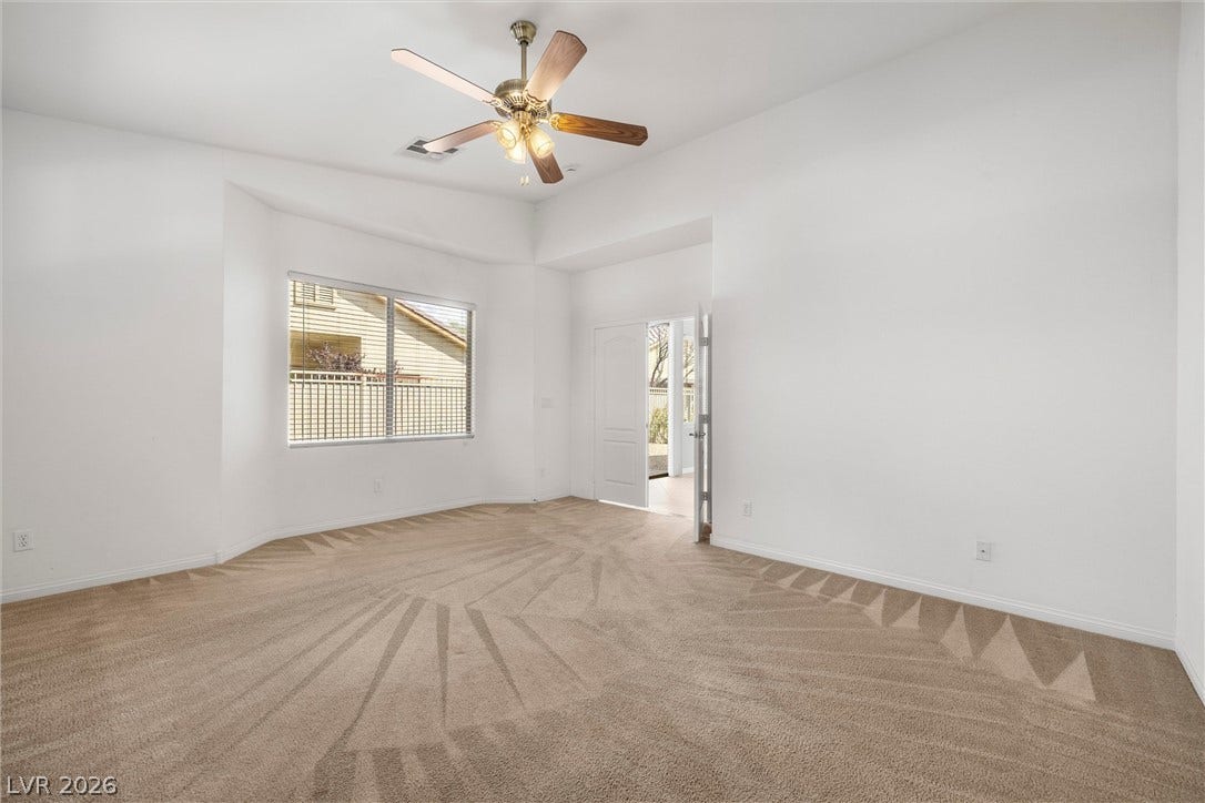5824 Pleasant Palms Street, North Las Vegas, NV 89081 A spacious carpeted bedroom features high ceilings and a wide window with plantation shutters.