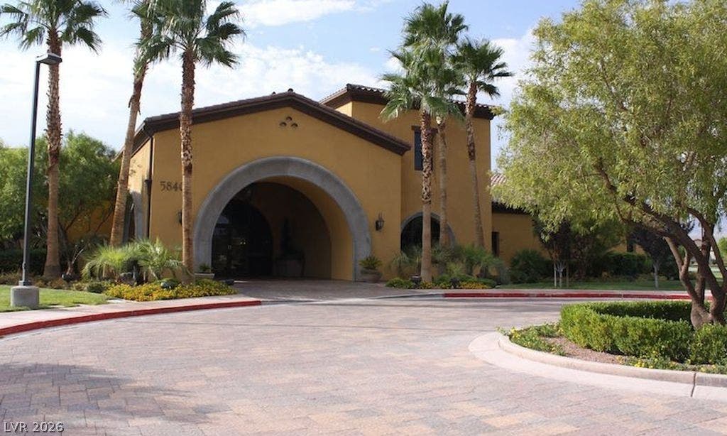 5824 Pleasant Palms Street, North Las Vegas, NV 89081 A grand arched entry welcomes visitors along a sweeping paved driveway lined with palm trees.