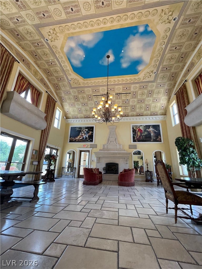 30 Via Vasari, #102, Henderson, NV 89011 An ornate coffered ceiling and grand stone fireplace anchor this majestic stone-tiled great room.