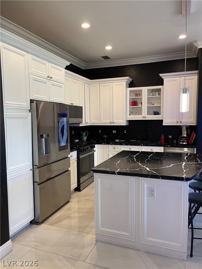 30 Via Vasari, #102, Henderson, NV 89011 Dramatic dark walls contrast beautifully with classic white cabinetry and a matching marbled center island.