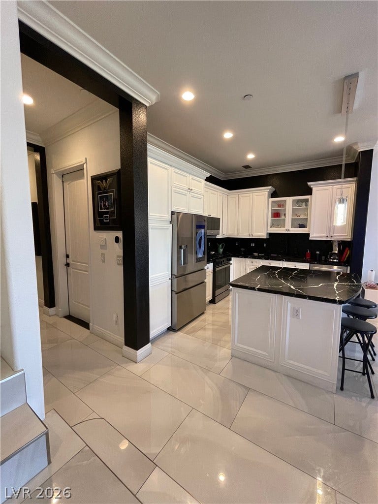 30 Via Vasari, #102, Henderson, NV 89011 Polished tile flooring guides the eye through a modern kitchen featuring a stone-topped island.