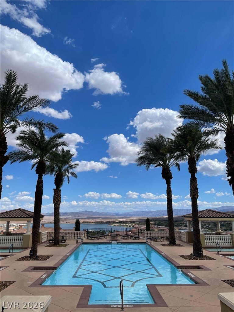 30 Via Vasari, #102, Henderson, NV 89011 Lush palm trees frame a sparkling swimming pool overlooking sweeping desert and water views.