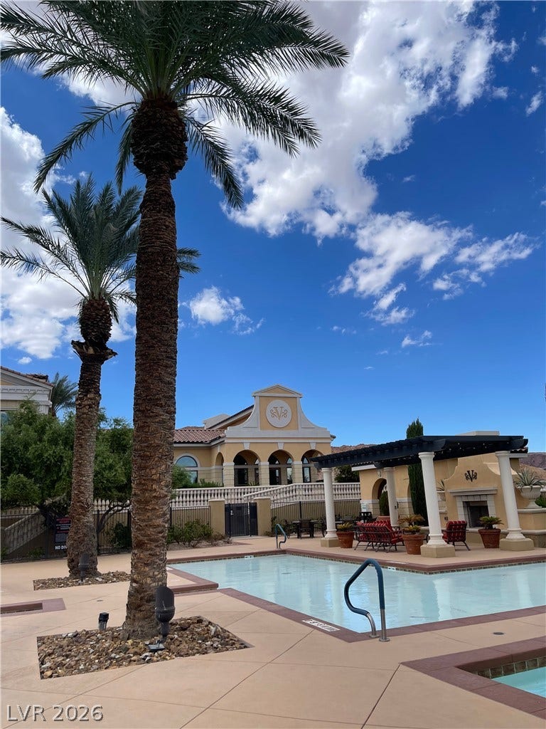 30 Via Vasari, #102, Henderson, NV 89011 Soaring palm trees frame a sparkling community pool set against a bright desert sky.