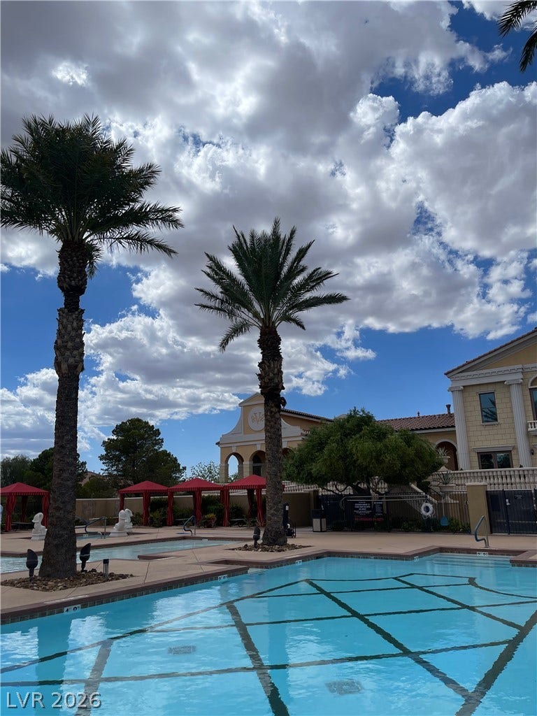 30 Via Vasari, #102, Henderson, NV 89011 Palm trees frame a sparkling community swimming pool under a cloud-filled sky.
