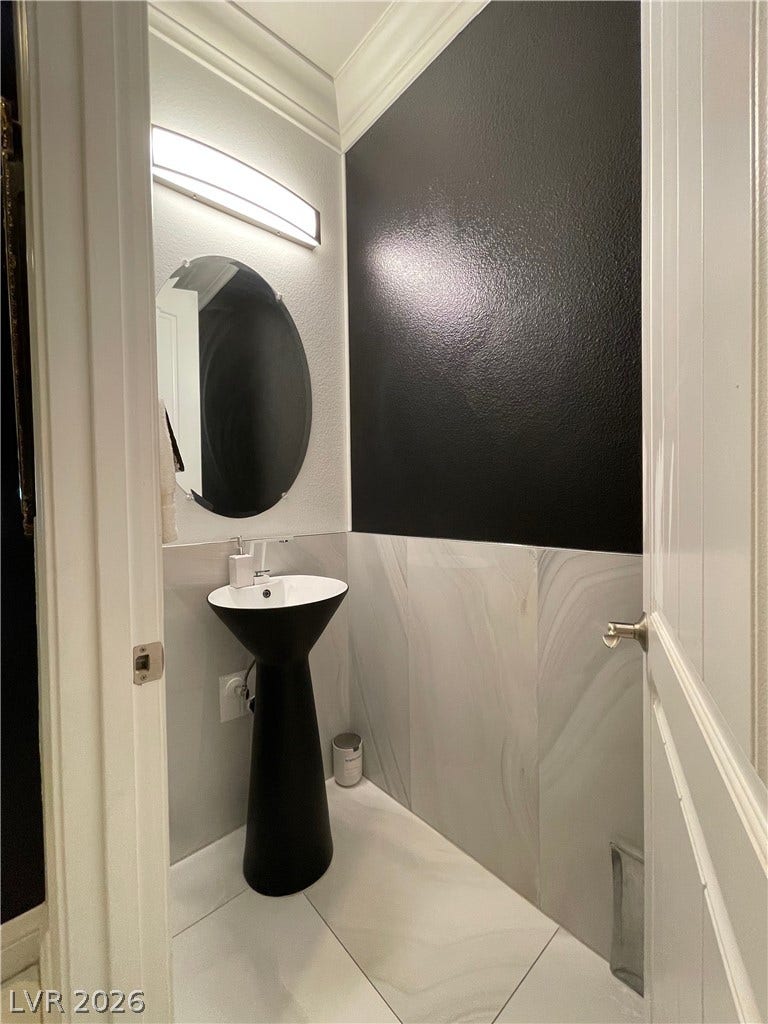 30 Via Vasari, #102, Henderson, NV 89011 Large-format stone tile flooring and wainscoting ground this modern powder room.