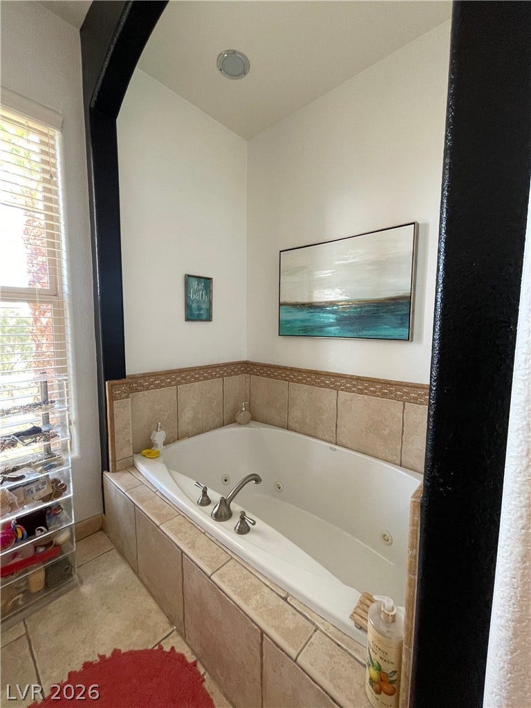 30 Via Vasari, #102, Henderson, NV 89011 An alcove soaking tub framed by tall ceilings and neutral tile surrounds.