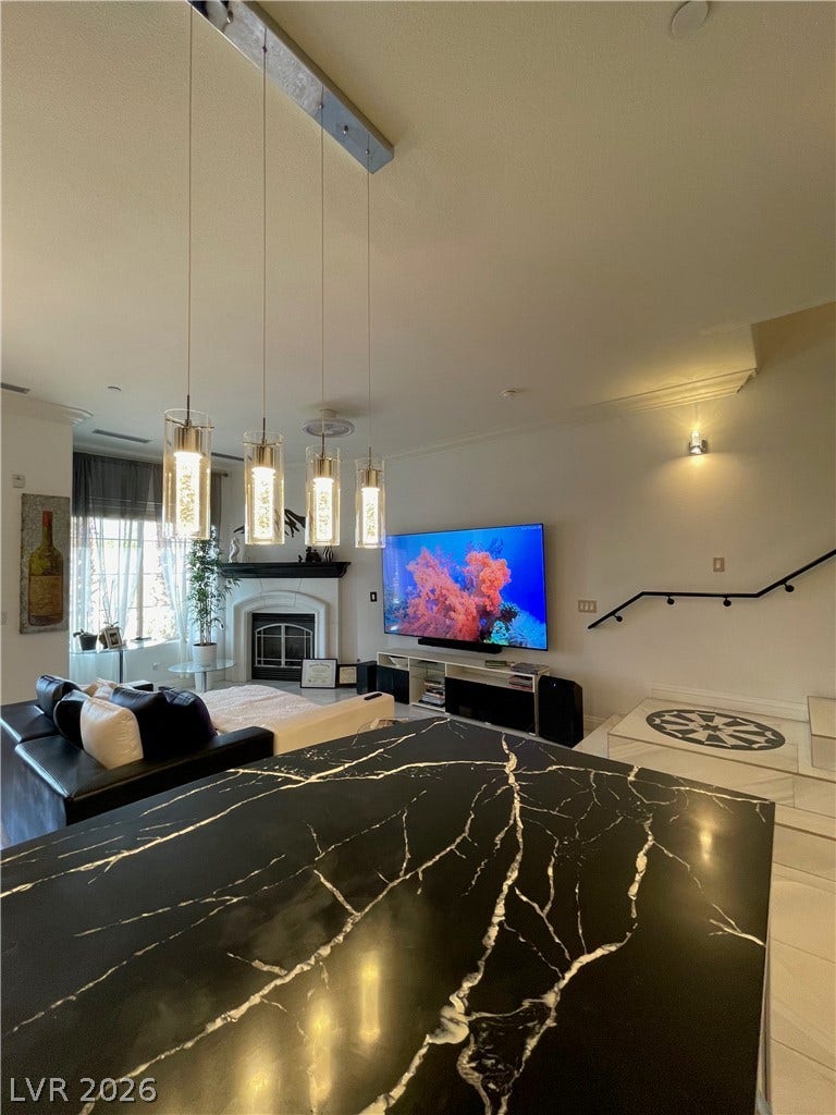 30 Via Vasari, #102, Henderson, NV 89011 Gleaming stone counters look out over an open living space centered around a classic fireplace.