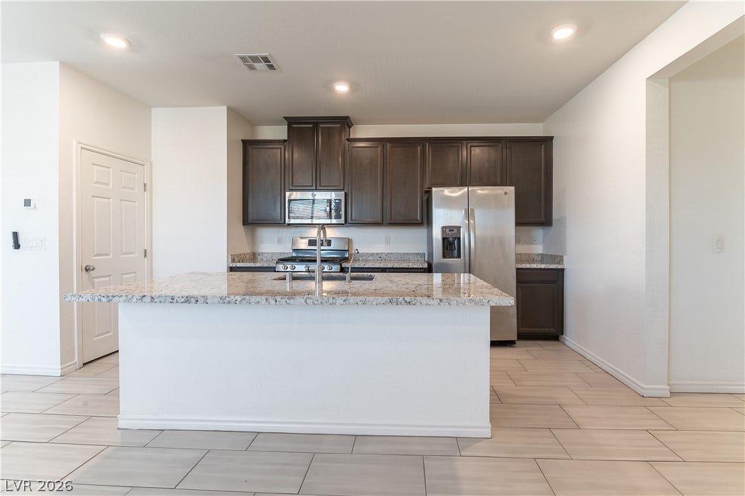 5740 Saltrock Grove Street, North Las Vegas, NV 89081 Rich dark cabinetry and a stone-topped island ground this modern culinary space.