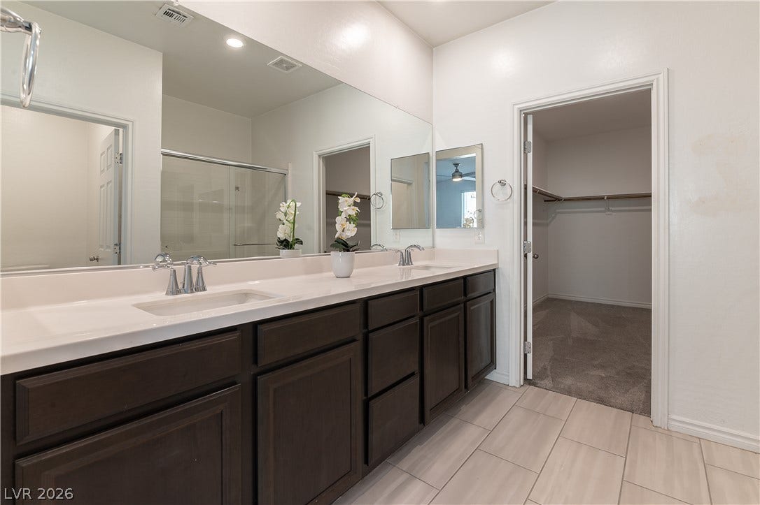 5740 Saltrock Grove Street, North Las Vegas, NV 89081 Double vanities with clean stone counters stand adjacent to a spacious walk-in closet.
