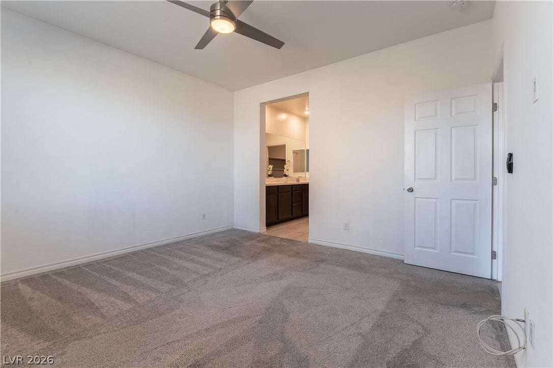 5740 Saltrock Grove Street, North Las Vegas, NV 89081 Plush carpeting anchors this spacious bedroom featuring clean lines and an attached en suite bathroom.
