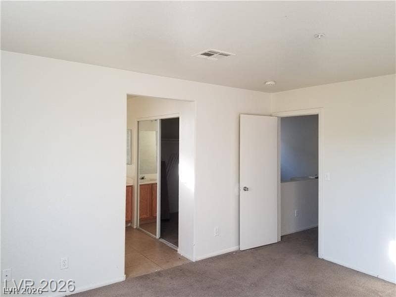3123 Inlet Bay Avenue, North Las Vegas, NV 89031 An open doorway leads from this carpeted bedroom into an adjacent bathroom with tiled flooring.