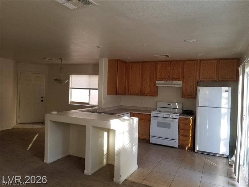 3123 Inlet Bay Avenue, North Las Vegas, NV 89031 An open kitchen layout pairs wood cabinetry with tiled floors and a functional breakfast bar.