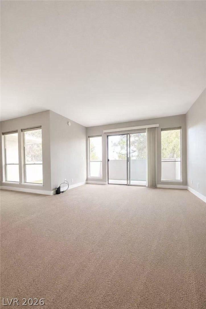 2838 Loveland Drive, #1608, Las Vegas, NV 89109 Broad windows and sliding glass doors fill the neutral living room with natural light.
