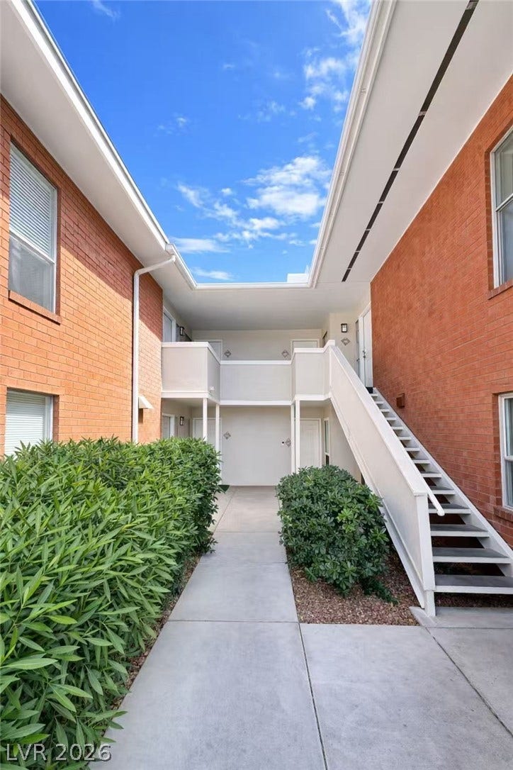 2838 Loveland Drive, #1608, Las Vegas, NV 89109 An open courtyard walkway is framed by classic brick siding and manicured green hedges.