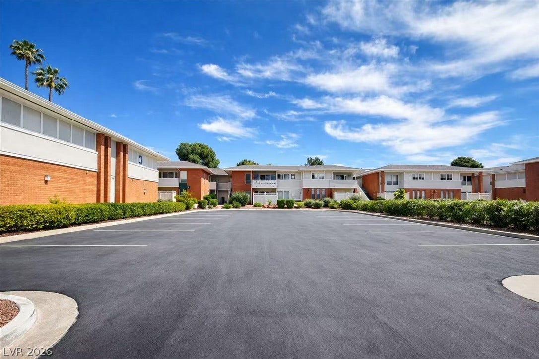 2838 Loveland Drive, #1608, Las Vegas, NV 89109 Brick and siding exteriors frame a large asphalt parking lot under a blue sky.