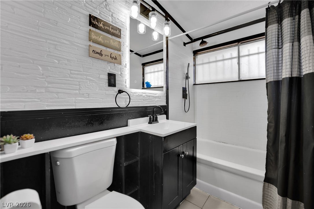 Textured brick wall details and dark trim accent this updated full bathroom.
