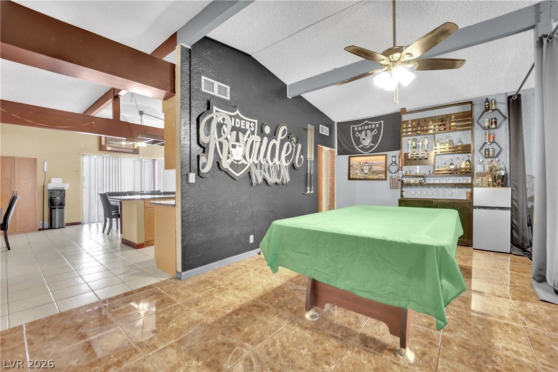 Soaring vaulted ceilings with exposed wood beams define this versatile open-concept living and recreation space.