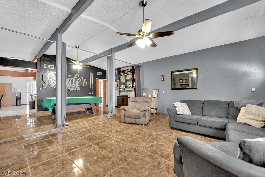 Gleaming tile floors and vaulted beamed ceilings define this generous recreation and living area.
