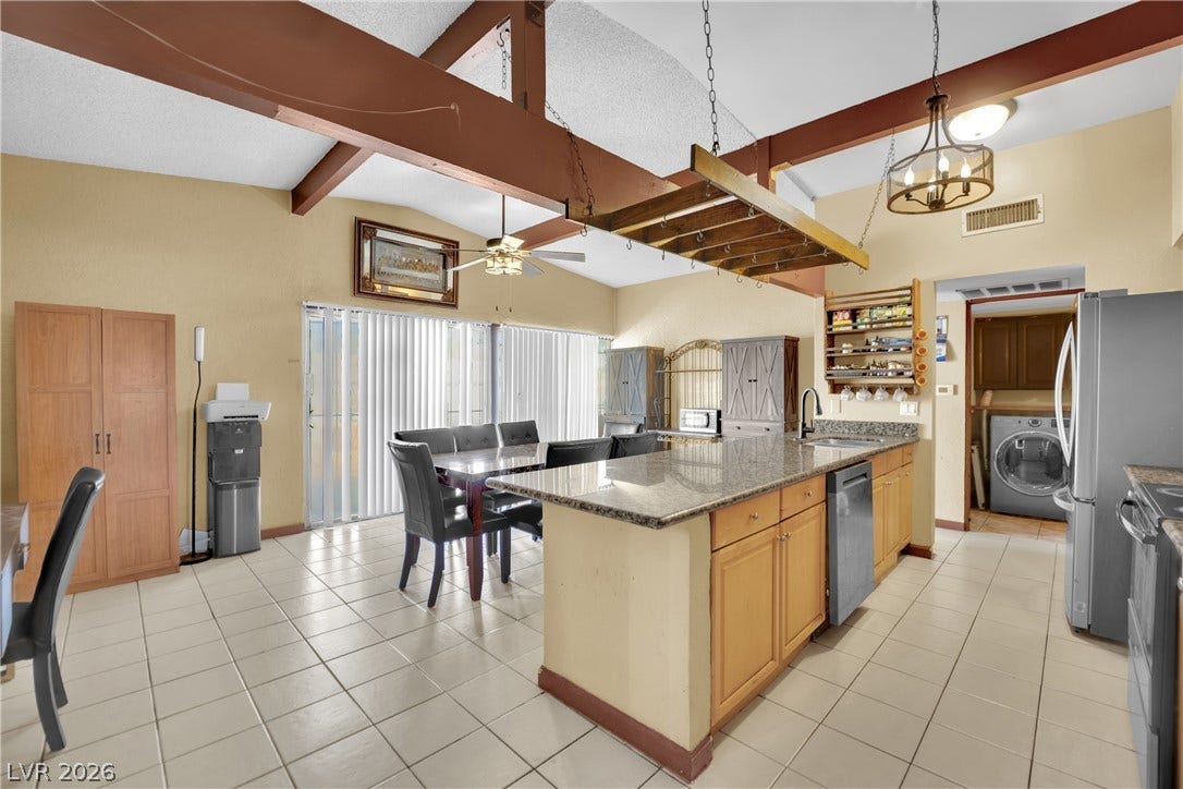 Exposed ceiling beams and durable tile floors define this airy open-concept kitchen and dining space.