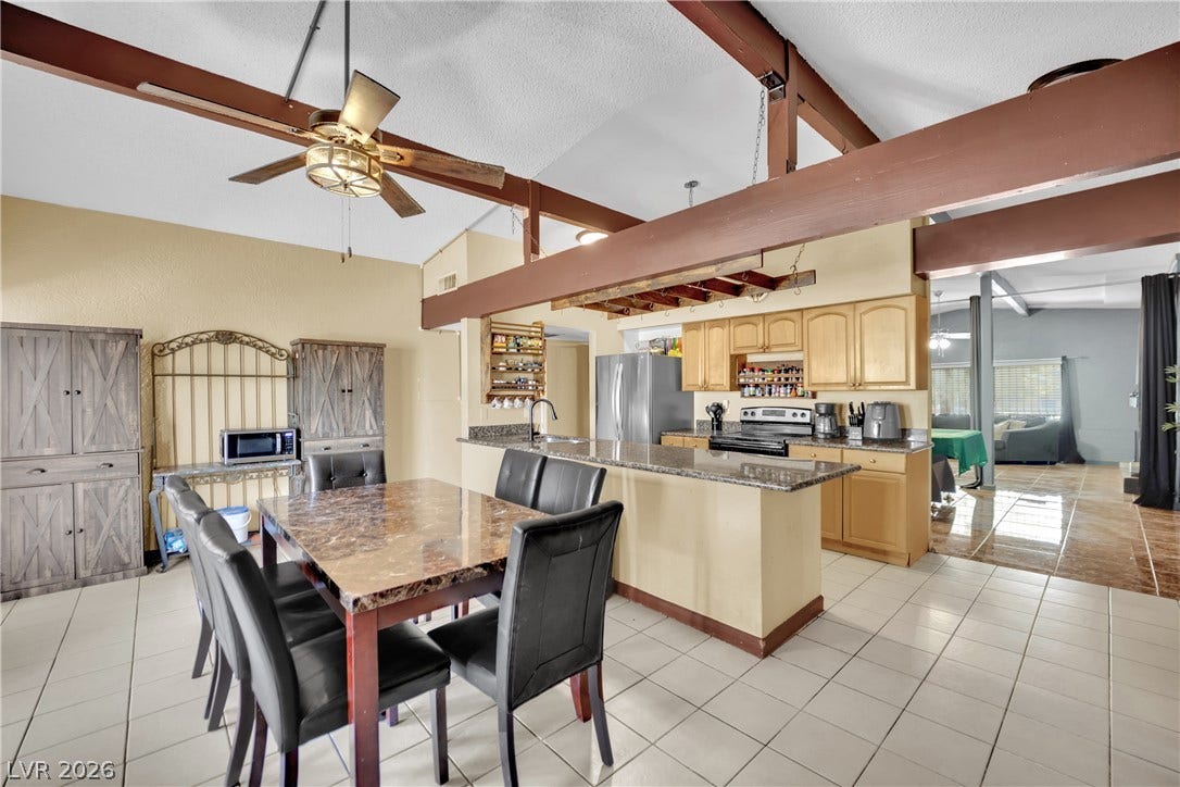 Exposed wooden beams soar above the open dining space and adjoining kitchen.
