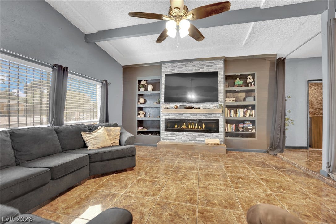 Warm tile floors and a stone fireplace accent this inviting living space with beamed ceilings.