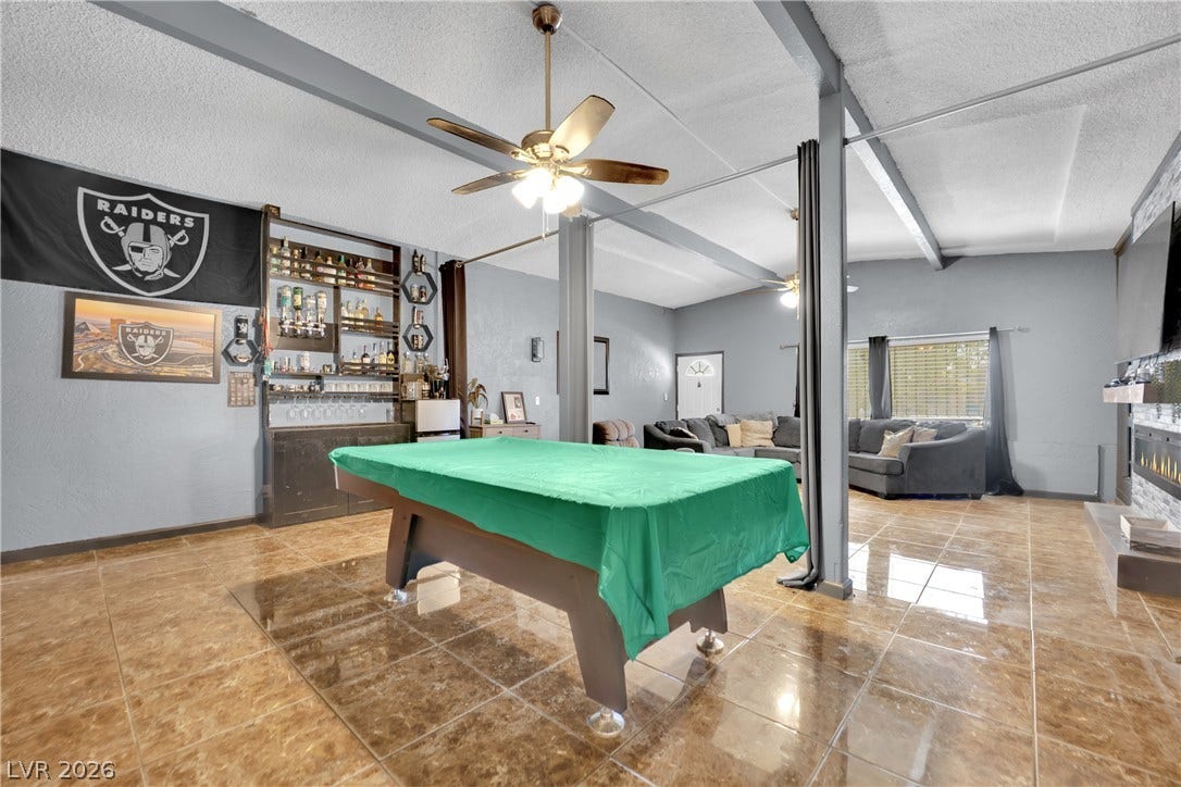 Exposed ceiling beams accent the sprawling tile flooring of this versatile recreation space.