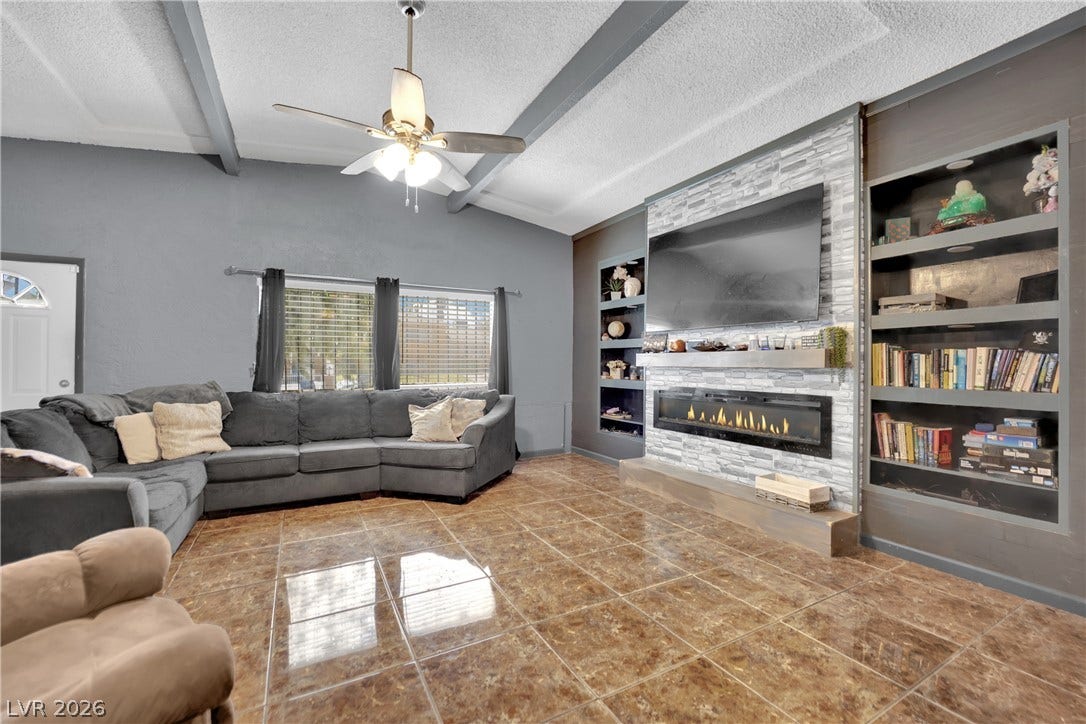 Glossy tile floors and a sleek fireplace under beamed ceilings define this welcoming space.