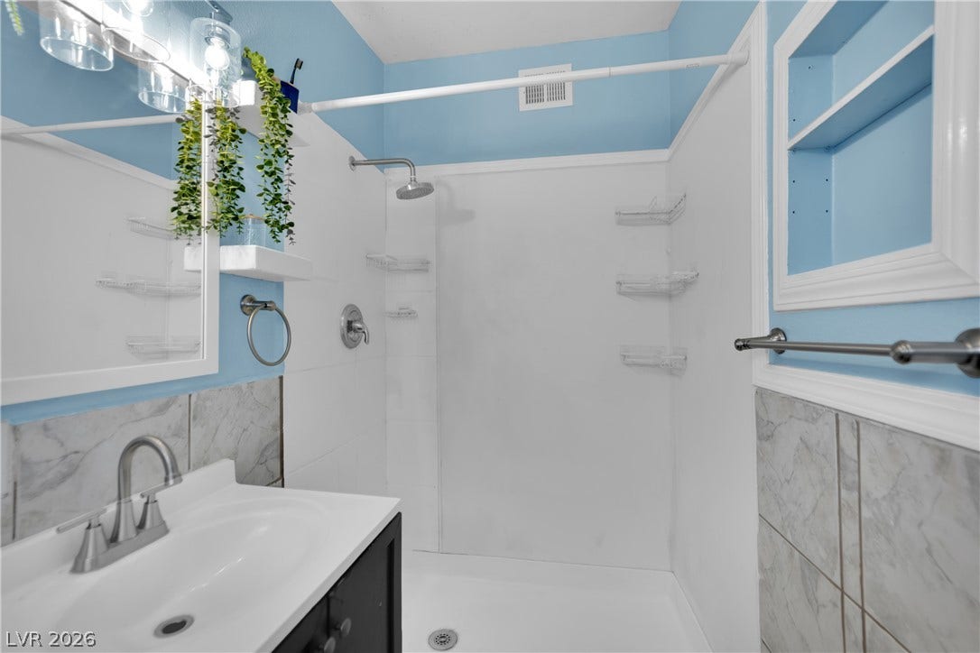 Clean lines and built-in wall shelving define this modern bathroom with a walk-in shower.