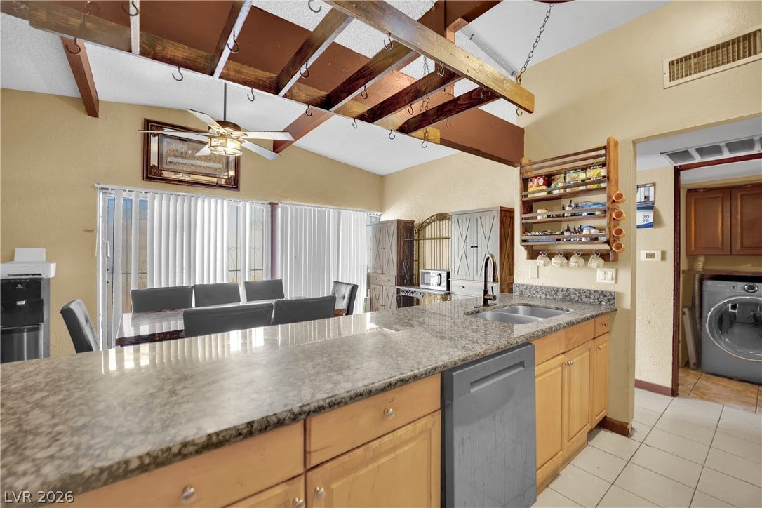 Exposed wood beams and durable granite countertops define this functional kitchen space.