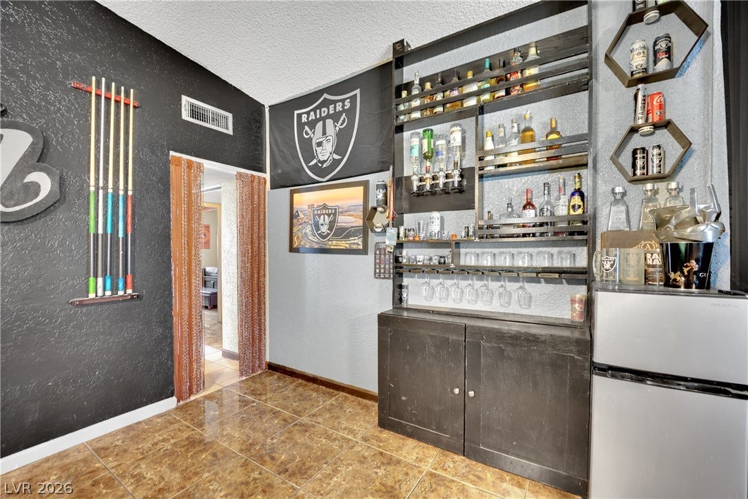 Polished tile flooring accents this dedicated home bar area featuring custom shelving and cabinetry.
