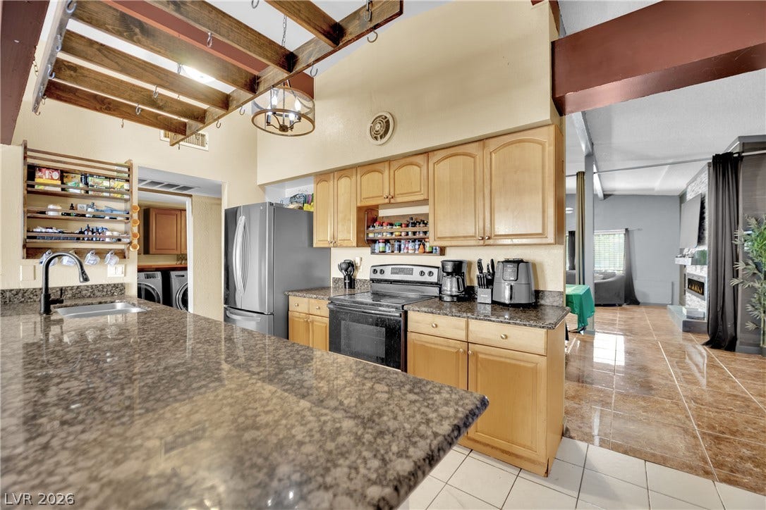 Polished stone countertops and open-concept sightlines highlight this spacious, well-appointed kitchen layout.