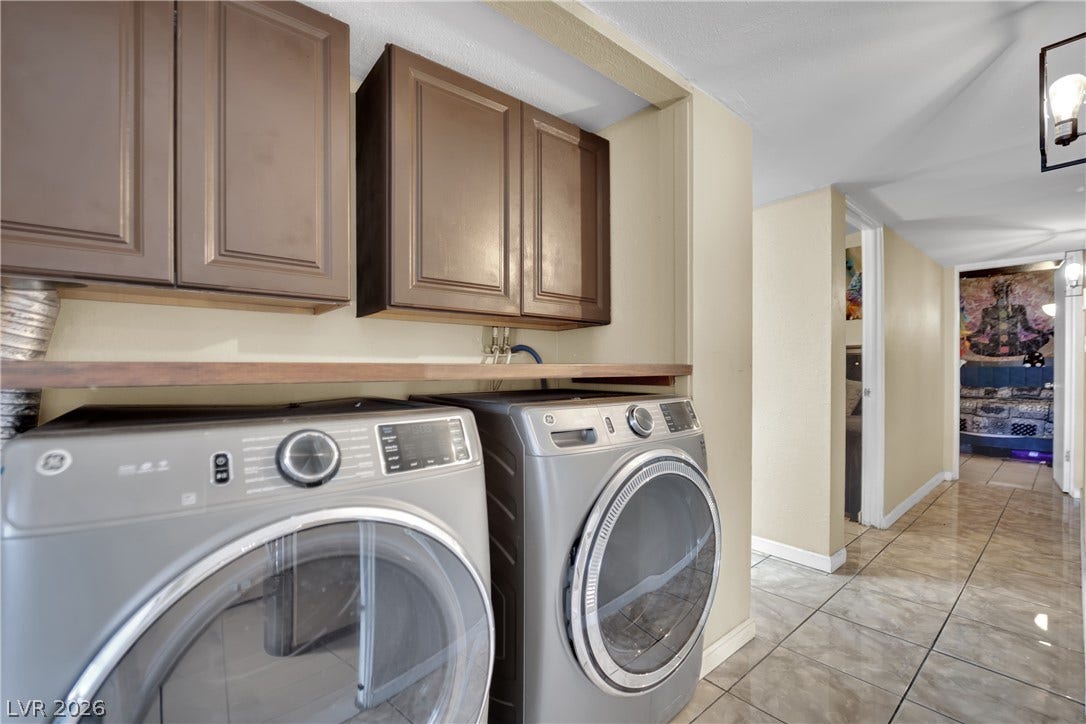 A dedicated laundry nook adjoins the tile-floored hallway, complete with overhead cabinetry and a folding counter.