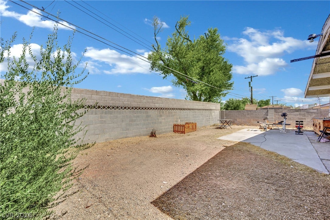An enclosed backyard area features a concrete patio section alongside a low-maintenance dirt yard.