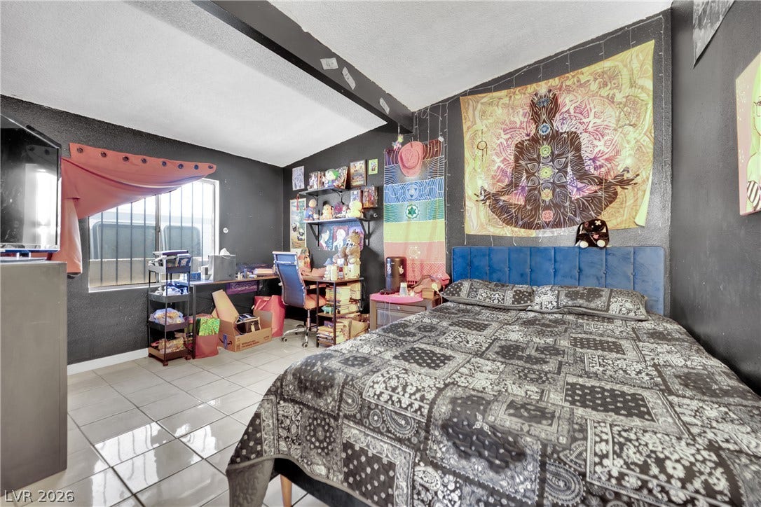 Glossy tile flooring and a contrasting vaulted ceiling detail define this comfortable bedroom space.