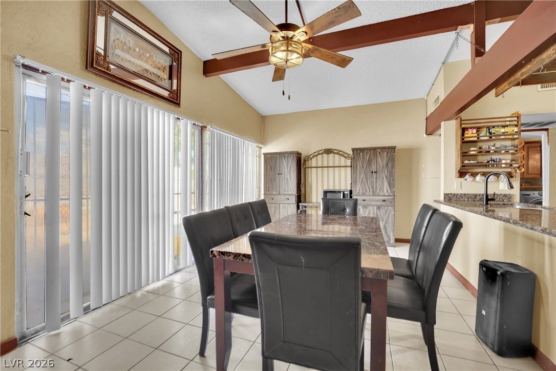 Exposed ceiling beams accent a bright dining area featuring tiled floors and sliding glass doors.