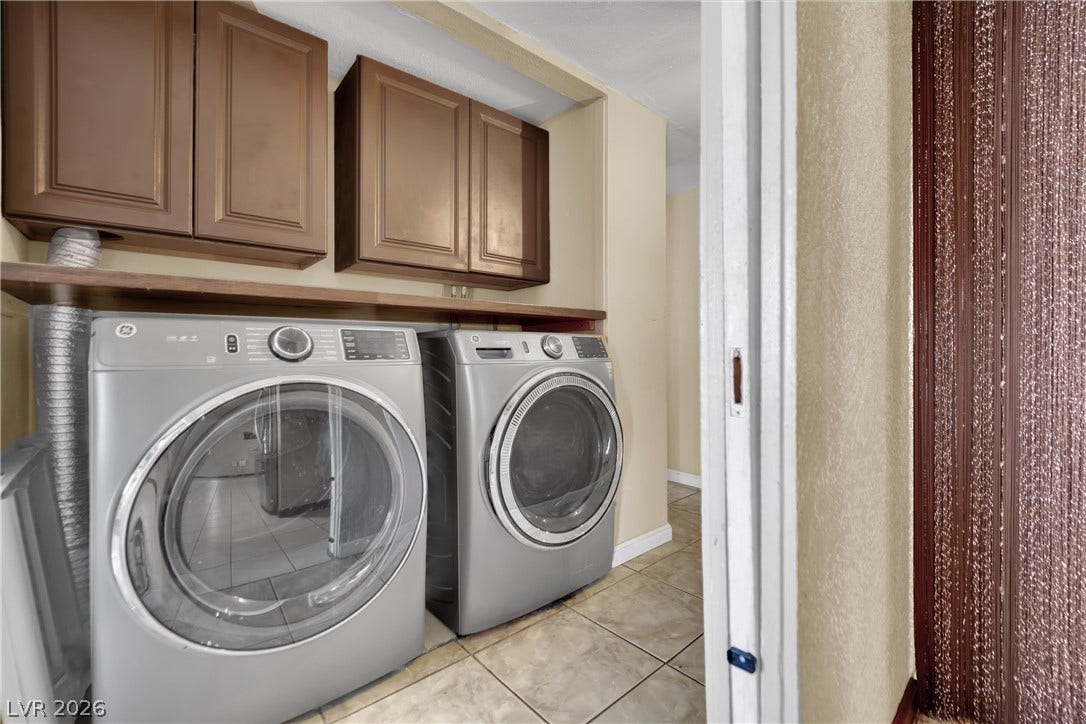 Functional laundry setup highlights tiled flooring and built-in overhead cabinetry.